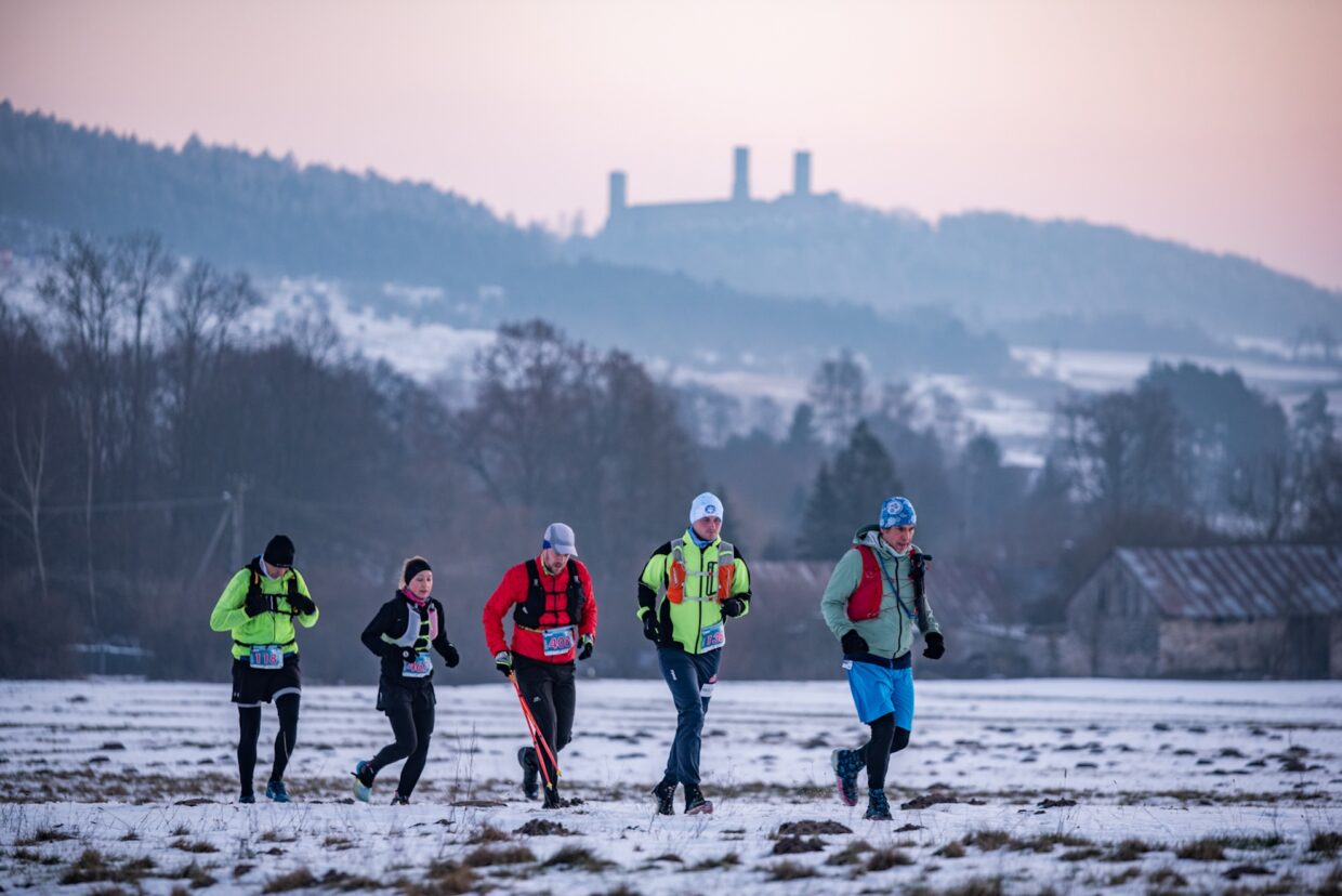 Na pierwszym planie: grupa uczestników zimowego maratonu świętokrzyskiego. W tle: Zamek Królewski w Chęcinach